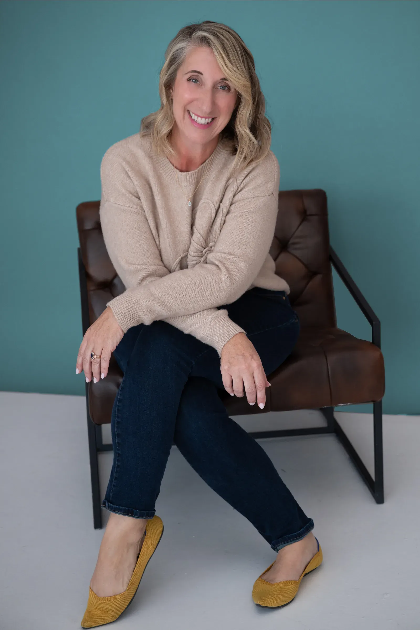 Dayne Whitehurst, smiling, seated in a leather chair against a teal wall
