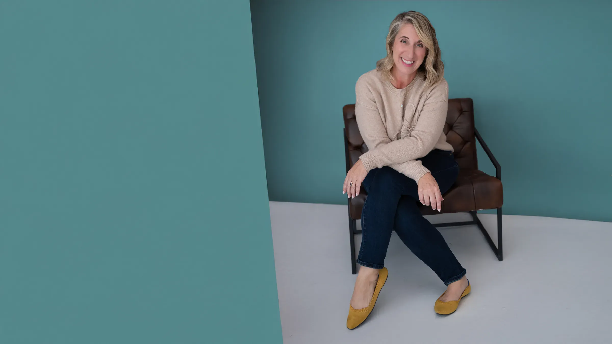 Dayne Whitehurst, smiling, seated in a leather chair against a teal wall